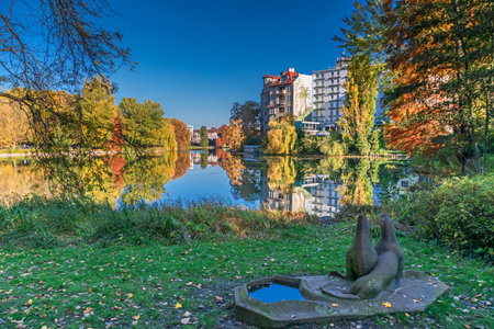 Berlin, Germany - November 7, 2020: Shore of Lake Lietzen with buildings of Haus See-Eck and Ringhotel Seehof and the stone sculpture Two sea lions with bird bathのeditorial素材