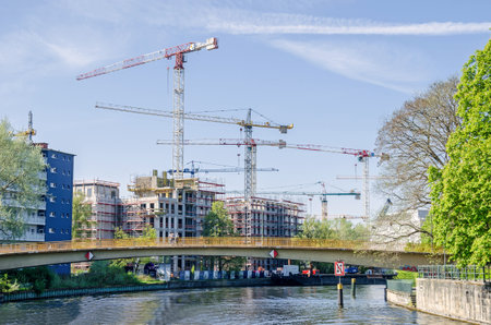 Berlin, Germany - April 22, 2018: Construction boom in the center of Berlin. View of new modern buildings and tower cranes from the river Spree with its arched footbridge Wullenweberstegのeditorial素材
