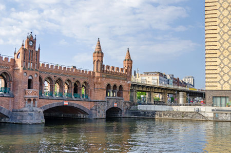 Banks of the river Spree with a part of the Brick Gothic viaduct Oberbaum Bridge with its wall walks and towers. View from the river.のeditorial素材