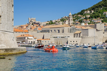 Dubrovnik, Croatia - June 9, 2017: The Old Harbor at Dubrovnik with the walls of the Old City, one of the most prominent tourist destinations in the Mediterranean Sea, filled with tourists and boats of all sorts.のeditorial素材
