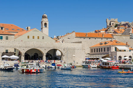 Dubrovnik, Croatia - June 9, 2017: The Old Harbor at Dubrovnik with the walls of the Old City, one of the most prominent tourist destinations in the Mediterranean Sea, filled with tourists and boats of all sorts.のeditorial素材