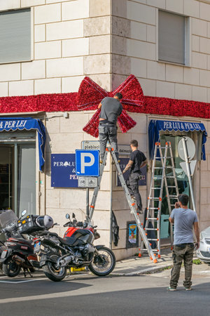 Civitavecchia, Italy - October 30, 2019: Locals decorating their street and condominium Largo Plebiscito No 4 for Christmas with a huge ribbon and a big bowのeditorial素材