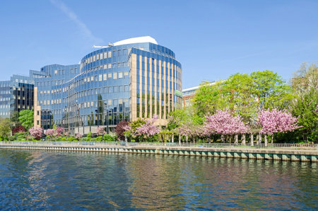 Reflecting facade of the buildings of Skandia insurance company on banks of the river Spree in Berlin with flowering trees in the springtimeのeditorial素材