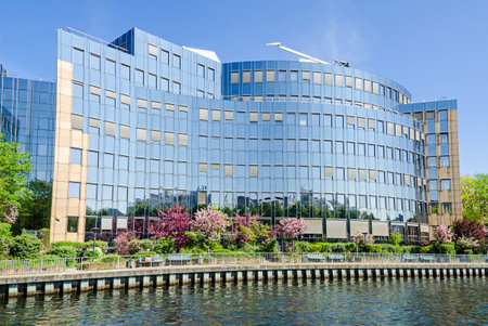 Reflecting facade of the buildings of Skandia insurance company on banks of the river Spree in Berlin with flowering trees in the springtimeのeditorial素材