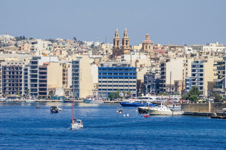 Sliema, Malta  - June 4, 2017:  Sliema Waterfront densely covered with  modern buildings, Sacro Cuor Parish Church and sailing boats as seen from Valletta.のeditorial素材