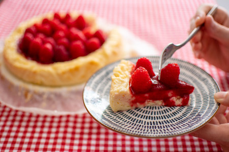 Close-up view of a woman hand holding a slice of cheesecake. Moment of eating.