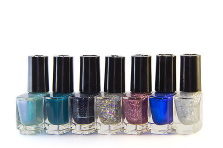 Glass bottles of nail polish with fashionable different shades of the year (blue, green, purple, violet) stand in a row, isolated on white backgroundの写真素材