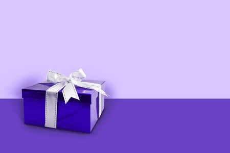 Gift box ultra violet color with white bow / ribbon  on a violet background with copy space.の写真素材
