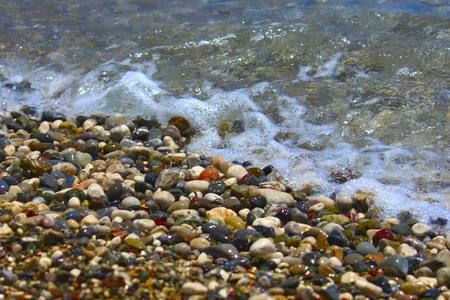 Bright colorful stones on the beach with clear clear water in Mediterranean Sea. Focus runs through the middle.の写真素材