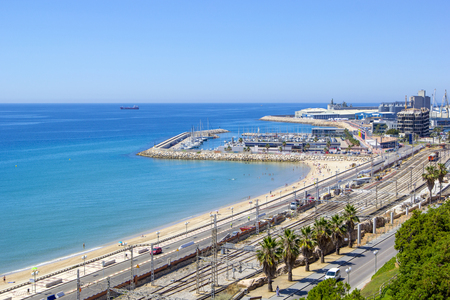 Panoramic view of coast of Tarragona, beach in La Pineda in sunny day with railway tracks along coastline and port with ships and yachts, Tarragona, Catalunya, Spainのeditorial素材