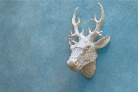 Decorative  deer head sculpture on cement blue wall, template, space for textの写真素材