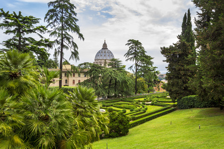 VATICAN, VATICAN CITY - JUNE 16, 2014: View at St Peter's Basilica (Basilica di San Pietro) from Vatican Gardens with beautiful green lawns, pines and palm trees, Rome, Italy.のeditorial素材