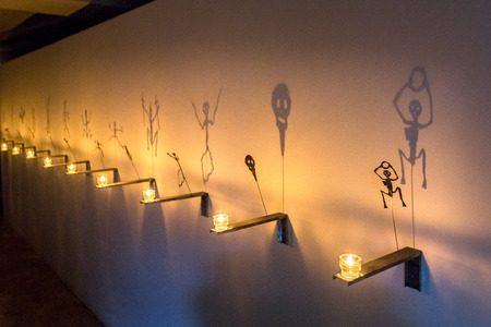Fabulous shadows of spider, skeleton, bat is reflected on wall from flame of candles standing in row. Black Ghost theatre of shadows, Holiday Halloween.の写真素材