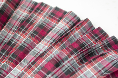 Detail of new fashion plaid pleated skirt: red, maroon, gray tartan school uniform fabric cotton/woolen material, blurred focusの写真素材