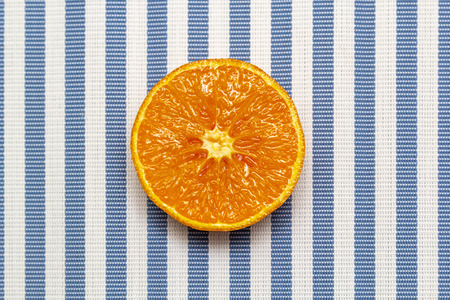 Top view of fresh orange slice fruit on white blue striped background. Minimal style, food concept, flat lay.の写真素材