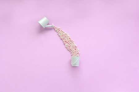 Watering can with splashing balls of candy in bucket. Round sweet peas sprinkle. Creative sweet concept. Flat lay, top view, copy spaceの写真素材