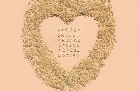 Letters of alphabet of pasta for kids food on light pink background. Pastel color for children's meals.の写真素材