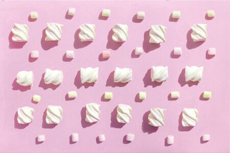Sweet beze, white marshmallows on pink background. Pastel color dessert. Top view, flat lay.の写真素材