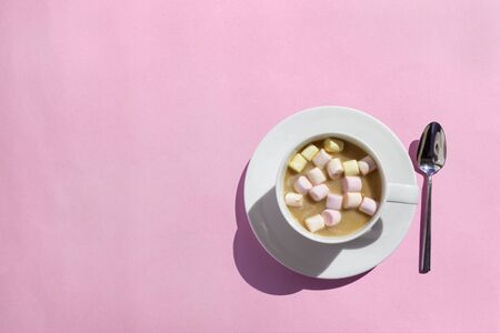 Cup of hot cocoa/coffee with marshmallows on pink table, top view, flat layの写真素材