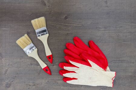 Paint brushes for repair and work gloves red on wooden background. Top view, flat layの写真素材