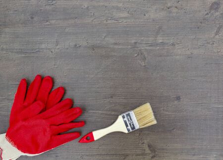 Paint brush for repair and work gloves red on wooden background. Top view, flat layの写真素材
