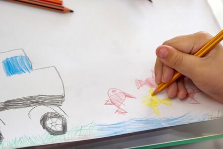 Child draws with colorful pencils. Children's drawing on theme of fishing with goldfish, car