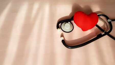 Stethoscope and red heart on natural light sources background, top view. Healthcare and medical concept.の写真素材