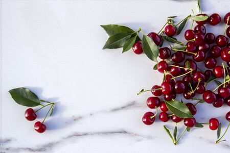 Colourful fresh bright pattern with ripe red cherry and leaf on marble table. Top view, flat layの写真素材
