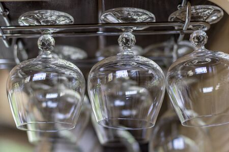 Clean empty cognac glasses in row hang on shelf bar in light sunshineの写真素材