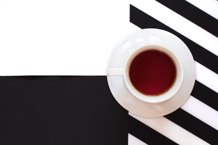 Cup of coffee / tea on black and white table with stripes in minimal style. Top view, flat lay with copy space.の写真素材