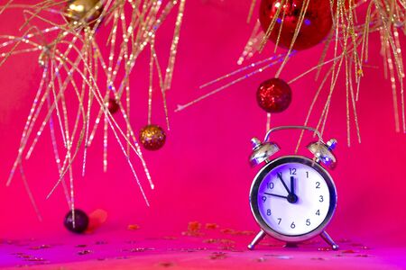 Christmas or New Year composition with alarm clock and beautiful gold decorations on red neon...