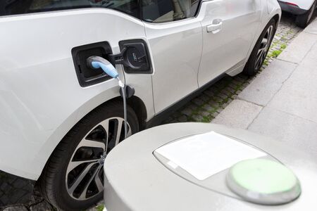 PARIS, FRANCE - MAY 10, 2019: Electric cars/ EV are charging at power supply station, parked along road. Concept of eco-friendly alternative energy.のeditorial素材