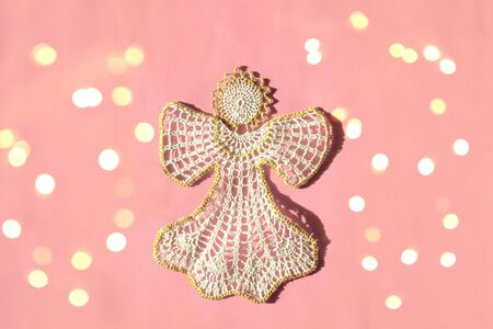 Christmas angel knitted bauble on pink New Year background with bright lights, flat lay, top viewの写真素材