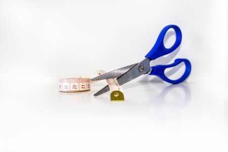 Scissors cutting measuring tape over white background, selective focus. Concept of work lifestyle, sewing clothes and atelier.の写真素材