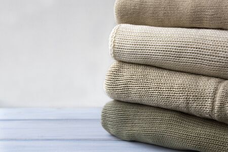 Stack of knitted woolen sweaters on light blue wooden table.  Folded autumn and winter clothing.の写真素材
