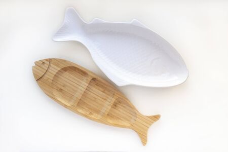 Empty wooden and ceramic plates fish shaped dish isolated on white background. Flat lay, top viewの写真素材