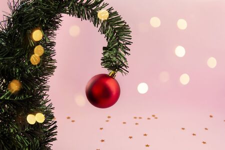 Christmas tree, creative branch with red ball on pink background with New Year lights, copy spaceの写真素材