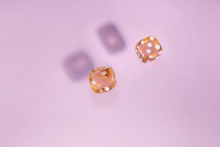 Two glass dice fall, bone to game on pink background. Concept for board games.の写真素材