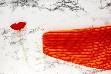 Sleeve of red sweater holds lollipop lips with sprinkles color sweet candy Ð¾n marble background, top view, copy space.の写真素材