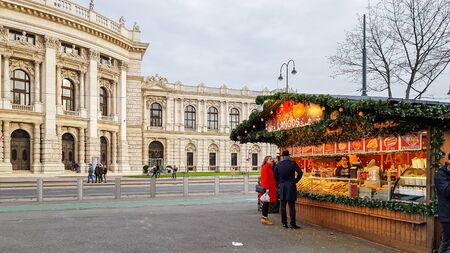 VIENNA, AUSTRIA - NOVEMBER 15, 2019: People buy Christmas baubles, toys and souvenirs at traditional Christmas market in front of City hall (Rathaus) and skating rink, Vienna, Austriaのeditorial素材