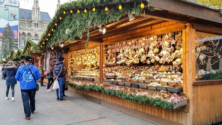VIENNA, AUSTRIA - NOVEMBER 15, 2019: People buy Christmas baubles, toys and souvenirs at traditional Christmas market in front of City hall (Rathaus) and skating rink, Vienna, Austriaのeditorial素材