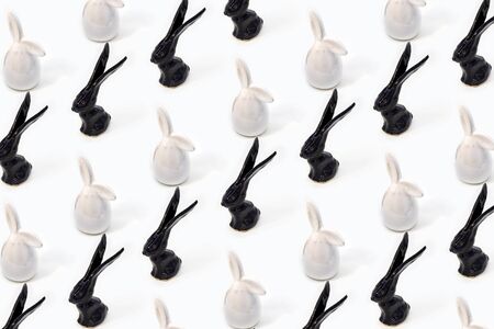 Trendy Easter pattern made of white and black rabbits hares toys on white isometric background in minimal style. Easter bunny concept in minimal style.の写真素材