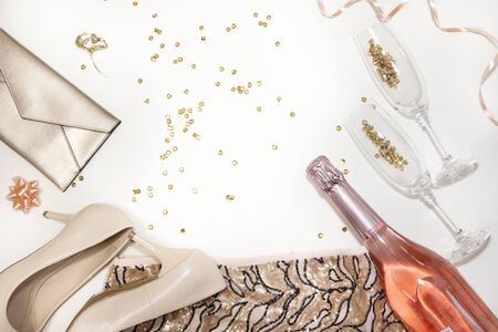 Set of women accessories party creative composition: shoes, decorations, glasses and bottle of champagne, clothes,  gifts, confetti on white background. Top view, flat lay, copy spaceの写真素材