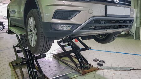 ST. PETERSBURG, RUSSIA - JUNE 17, 2019: Car in repair station, body shop on hydraulic lifts in modern automotive dealership maintenance garage.のeditorial素材