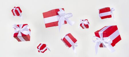 Banner red gift boxs with white satin ribbon bow flying on white background. Minimal concept for christmas holidays, birthday, valentine, shopping and sales.の写真素材
