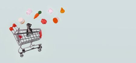 Metal grocery shopping basket, shopping car with products flying into it on light blue background, isolated, banner. Concept of shopping, salesの写真素材