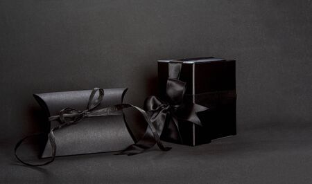 Two black gift boxes with black ribbon bow on dark background, copy space. Valentine's day, birthday romantic concept, greeting card.の写真素材
