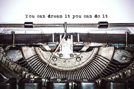 Old vintage typewriter, retro machine with white sheet of paper and typed text "you can dream it you can do it", copy space, close upの写真素材