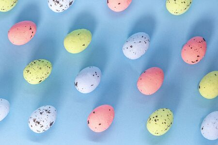 Trendy Easter pattern made of colored eggs on blue isometric background in minimal geometry style....
