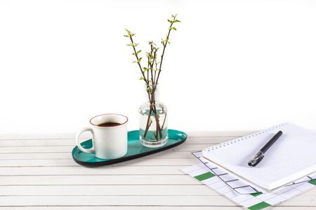 Home office workspace mockup with notebook, pen, cup of coffee, branch in glass vase and accessories...